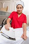 Portrait d'une employée portant bandana pendant le repassage à la laverie automatique