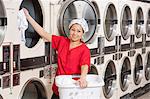 Portrait of a happy young female employee putting clothes in washer