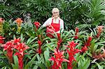Portrait of a happy senior florist watering plants in greenhouse