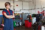 Portrait of a confident young female mechanic with arms crossed in garage