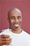 Portrait d'un jeune homme heureux avec le verre de lait sur fond coloré