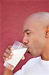 Vue latérale d'un homme afro-américain buvant du lait sur fond coloré