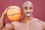 Portrait of a young African American man with basketball on shoulder over colored background