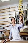 Young craftsman holding equipment in frame workshop