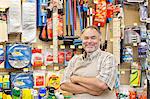 Portrait of a happy mature salesperson with arms crossed in hardware store