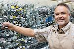 Portrait of a happy mature salesperson holding metallic equipment in hardware store