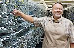 Happy mature salesperson holding metallic equipment while looking away in hardware store