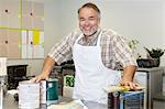 Portrait of a cheerful mature sales clerk with paint can in hardware store