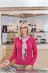 Portrait of a senior optometrist wearing glasses in store