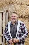 Portrait of a happy mature man in front of hay stack