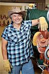 Portrait of a happy mature cowboy standing by saddle in feed store