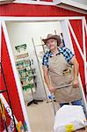 Mature cowboy pushing cart with sack in feed store