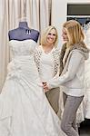 Glückliche Mutter und Tochter schauen Schönes Brautkleid im Hochzeits-Shop