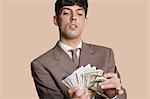 Young businessman counting money over colored background