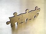 Three steel jigsaw against a metallic background