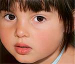 Face of a little girl with rosebud shaped lips and large brown eyes.