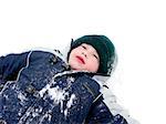 Young boy lying in snow enjoying winter