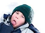 Young boy playing in snow, sticking his tongue out
