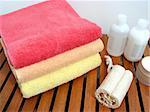 Spa or bathroom accessories: stack of colorful towels, loofah sponge, lotions, shampoos, creams