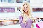 Beautiful girl with shopping bags and credit card at the store