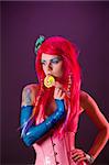 Bright girl with pink hair holding lollipop, studio shot