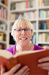 Portrait of happy retired caucasian woman with eyeglasses reading book at home