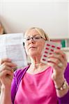 Elderly caucasian woman with medicine and reading drug prescription. Copy space