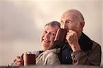 Adorable senior couple outdoors drinking from mugs