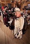 Old west cowboy and group point their weapons in a saloon