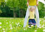 Mother playing with baby girl on dandelions field