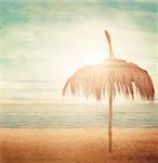 Straw parasol with cloudscape and calm sea water on sand beach on a tropic island