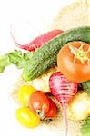 various vegetables (tomatoes, radishes, cucumbers) on a white background