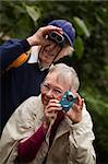 Elderly tourists with camera and binoculars in the woods