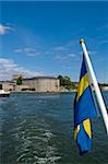 Swedish flag and Vaxholm fortress as seen from the water, Stockholm archipelago, Sweden