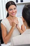 Beautiful young Latina Hispanic woman or businesswoman in smart business suit sitting at a desk in an office having a meeting