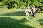 Active retirement, senior couple running and exercising in city park. Copy space