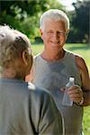 Senior people, old man and woman talking and drinking water after exercising in park