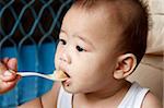 Mother feeding hungry baby in highchair