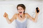 Portrait of girl laying on bed and listening music. Upper view