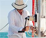The captain of a yacht raising the mainsail