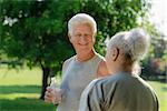 Senior people, old man and woman talking and drinking water after exercising in park