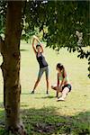 Two beautiful women stretching in city park after running and sport activity