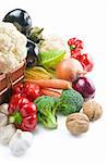 Mix of fresh ripe vegetables placed in a wicker basket and around isolated on white background.