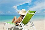 Young woman with hat relaxing on a deck chair