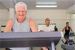 People and sports, elderly man working out on treadmill in fitness gym among young people