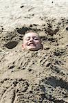 Child covered with beach sand