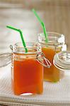 Carrot and orange juice and peach juice in preserving jars with straws