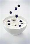 Blaubeeren fallen in eine Schüssel mit Joghurt