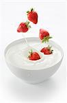 Strawberries falling into a bowl of yogurt