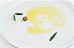 Olive oil, green olives and olive leaves on a plate